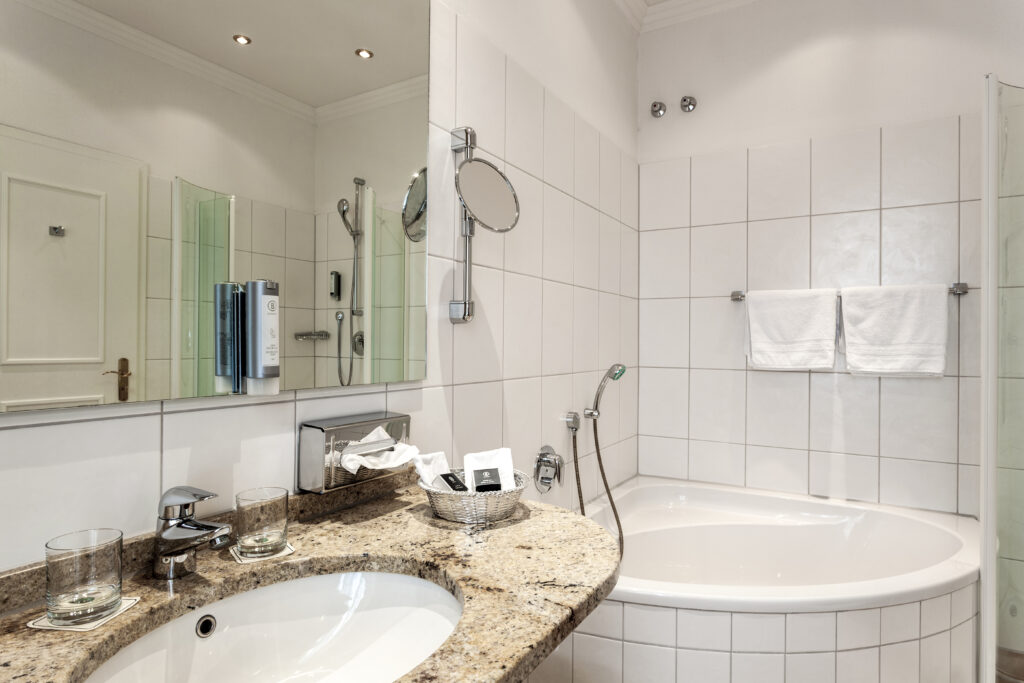 Das Badezimmer im Hotel in Günz, eine große Wanne zum Duschen, in schönem Weiß.