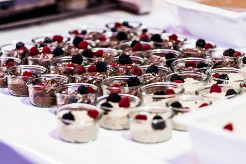 Feine Desserts in kleinen Glasschälchen auf weißem Untergrund.