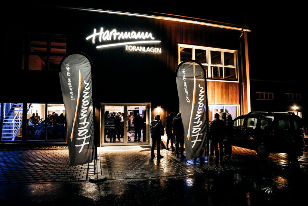 Wir catern bei der Firma Hartmann Toranlagen, hier der tolle Eingang mit großem beleuchteten Schriftzug und Fahnen davor.