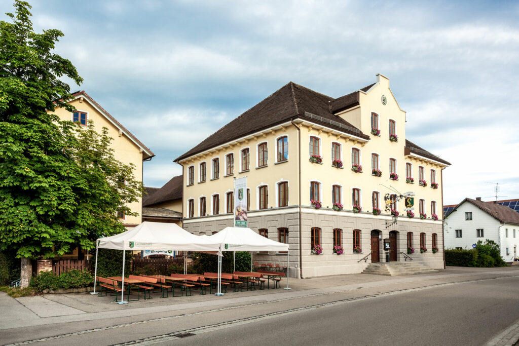Unser Brauergasthof-Hotel in Günz. Ein imposantes Gebäude, gelb gestrichen mit vielen Fenstern und dem Laupheimer Wappen unter dem Dach.
