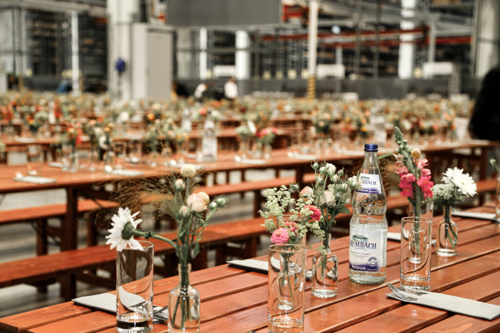Schön gedeckte Tische mit Blumen und Wasser stehen für die ersten Gäste beim Firmenevent von Liebherr bereit.