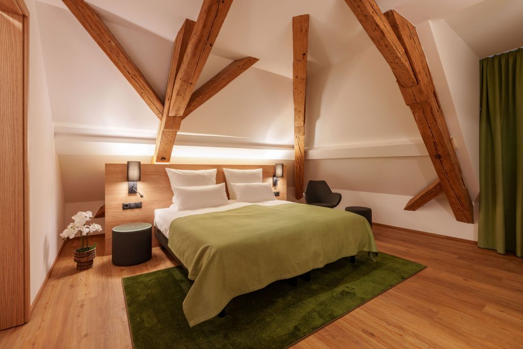 Stilvolles Doppelzimmer mit freigelegten Holzbalken im Brauereigasthof-Hotel Laupheimer in Günz im Allgäu, nahe Flughafen Memmingen – moderne Ausstattung und gemütliche Atmosphäre.