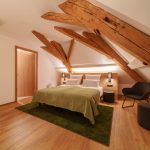 Helles Dachgeschoss-Hotelzimmer mit freigelegten Holzbalken im Brauereigasthof Laupheimer in Günz im Allgäu, nahe Flughafen Memmingen – modernes Design, großzügiger Raum und hoher Komfort.