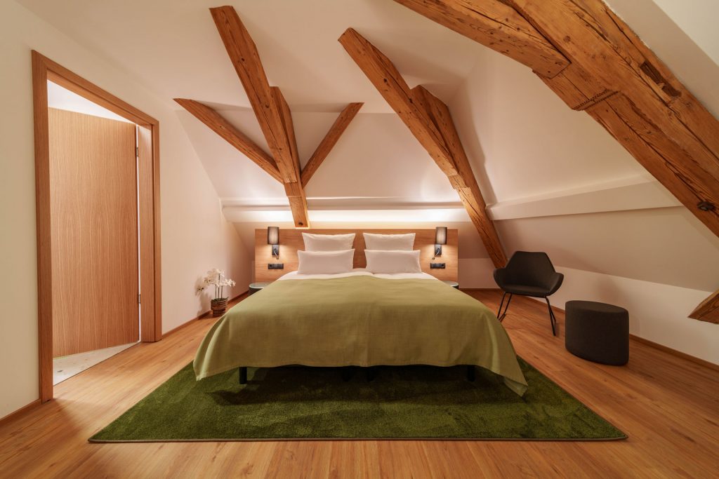Modern eingerichtetes Doppelzimmer mit sichtbaren Holzbalken im Brauereigasthof-Hotel Laupheimer in Günz im Allgäu, nahe Memmingen Flughafen – stilvolle Kombination aus Tradition, Komfort und hochwertiger Ausstattung.